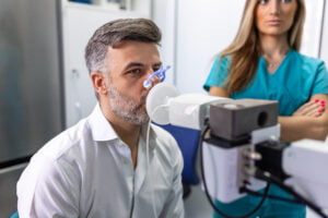 Man performing lung function testing and spirometry using spirometer at medical clinic.